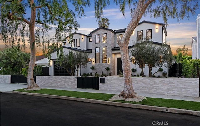 view of front of home featuring stucco siding, stone siding, and a fenced front yard