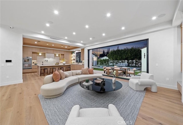 living area with recessed lighting, light wood-style floors, and baseboards