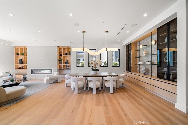 dining area featuring light wood-type flooring, built in features, and recessed lighting