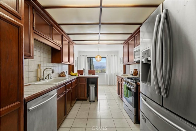 kitchen featuring tile counters, backsplash, stainless steel appliances, and light tile patterned flooring