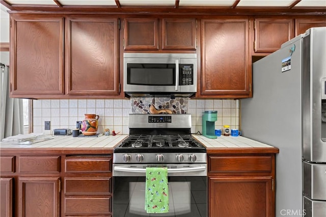 kitchen featuring backsplash, stainless steel appliances, tile counters, and tile patterned floors
