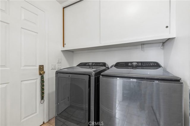 laundry area with cabinet space, separate washer and dryer, and light tile patterned floors