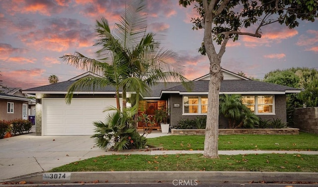 view of front of home with an attached garage, stucco siding, a front yard, and concrete driveway