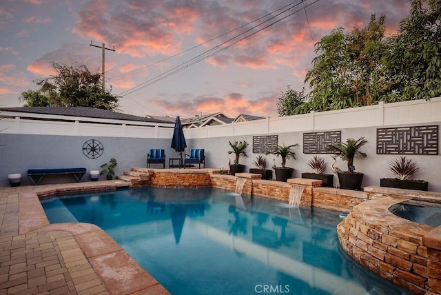 pool at dusk featuring a fenced in pool, a fenced backyard, an in ground hot tub, and a patio area