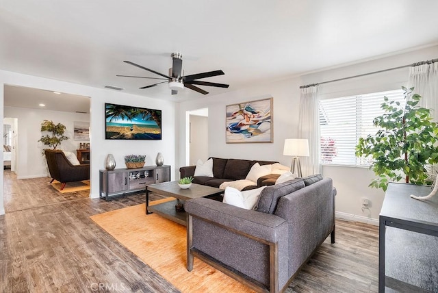 living room featuring baseboards, ceiling fan, wood finished floors, and visible vents