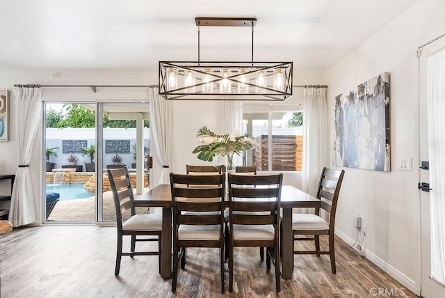 dining room featuring baseboards, wood finished floors, and a notable chandelier