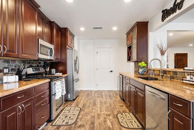 kitchen featuring a sink, appliances with stainless steel finishes, light stone counters, and visible vents
