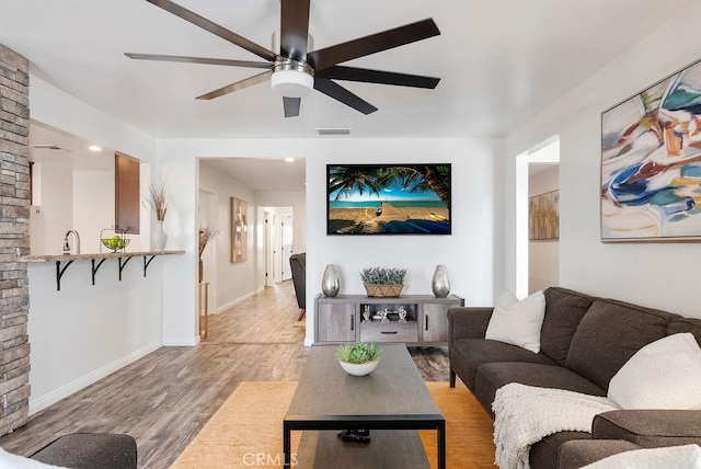 living room featuring baseboards, ceiling fan, visible vents, and wood finished floors
