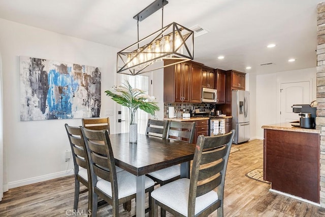 dining space featuring visible vents, light wood finished floors, and baseboards