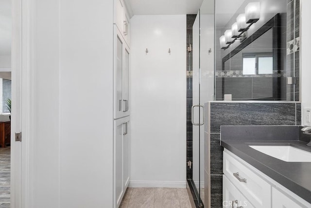 bathroom featuring vanity, baseboards, and a stall shower