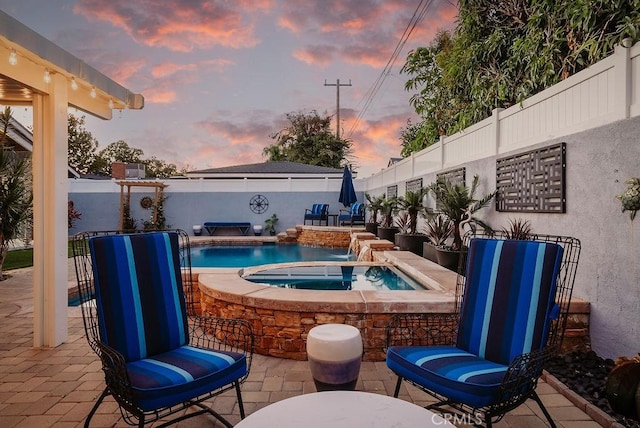 view of patio featuring a fenced backyard, a fenced in pool, and an in ground hot tub
