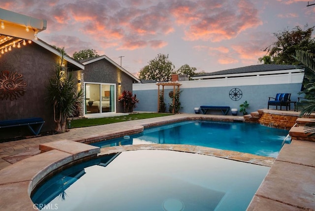 pool at dusk with a patio, an in ground hot tub, fence, and a fenced in pool