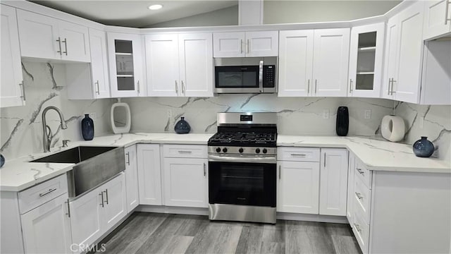 2108 Raleigh Ave, Costa Mesa, CA 92627 - kitchen featuring appliances with stainless steel finishes, a sink, white cabinetry, glass insert cabinets, and vaulted ceiling