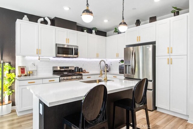 3630 E Peckham Paseo Unit 4, Ontario, CA 91761 - kitchen with appliances with stainless steel finishes, a sink, light countertops, light wood-style flooring, and a kitchen island with sink