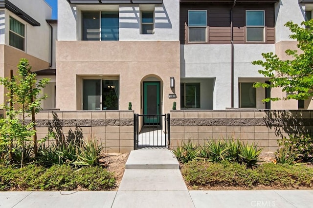 view of front of house with a gate, a fenced front yard, and stucco siding
