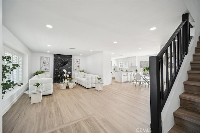 living area with light wood-type flooring, recessed lighting, and stairway