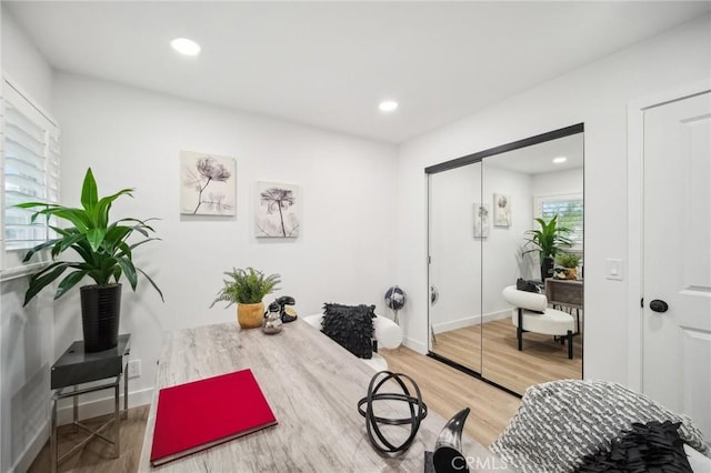 exercise room featuring baseboards, light wood finished floors, and recessed lighting