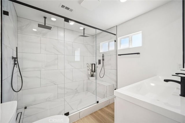 full bathroom with a shower stall, wood finished floors, visible vents, toilet, and a sink