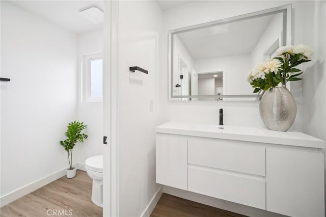 bathroom featuring baseboards, wood finished floors, vanity, and toilet
