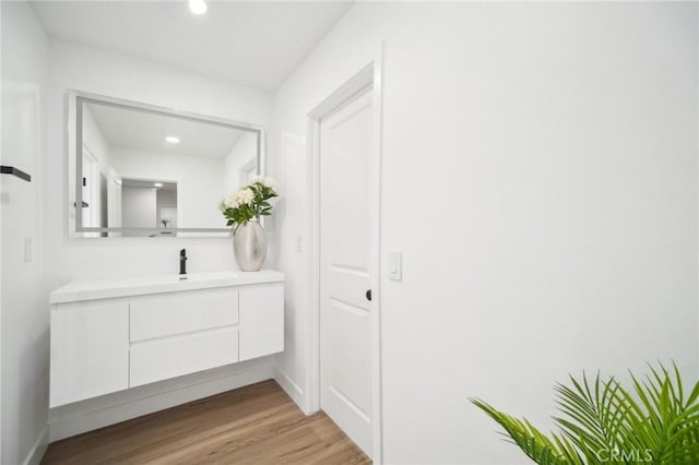 bathroom with wood finished floors, vanity, and recessed lighting