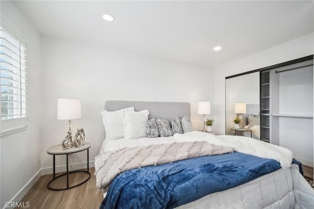 bedroom with baseboards, wood finished floors, and multiple windows