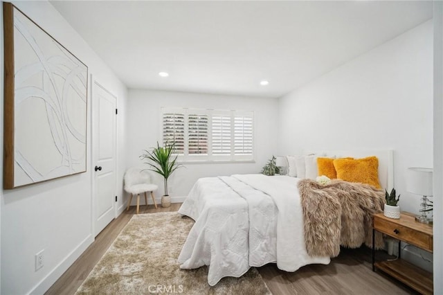 bedroom featuring baseboards, wood finished floors, and recessed lighting