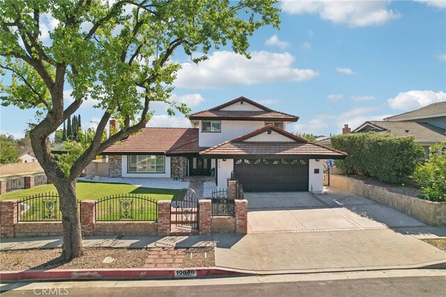 view of front facade featuring a gate, a tile roof, a fenced front yard, driveway, and an attached garage