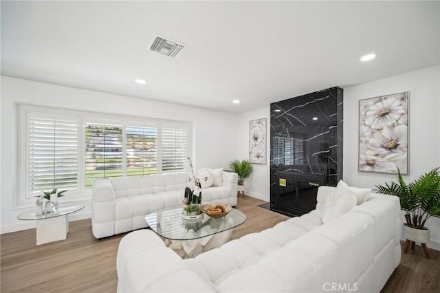 living area with recessed lighting, wood finished floors, visible vents, and baseboards