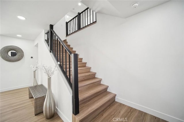 staircase featuring recessed lighting, wood finished floors, and baseboards