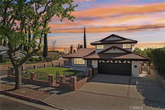 traditional home featuring an attached garage, concrete driveway, a gate, and a fenced front yard