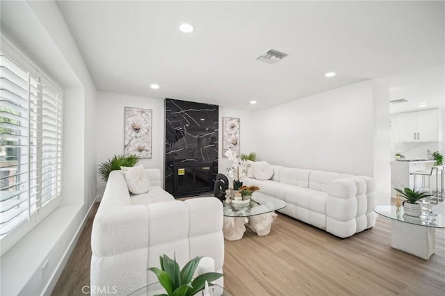living area featuring recessed lighting, wood finished floors, visible vents, and plenty of natural light