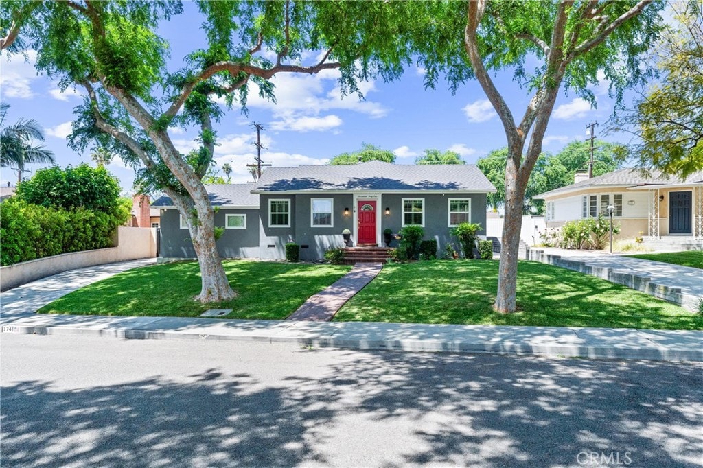 bungalow with stucco siding, a garage, a front lawn, and fence