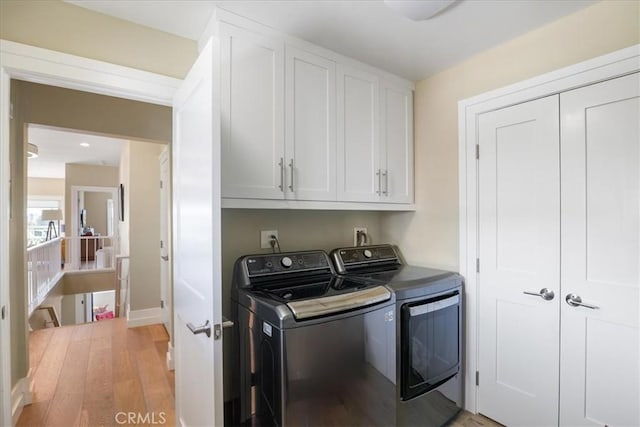 laundry room with cabinet space, light wood-style flooring, and separate washer and dryer
