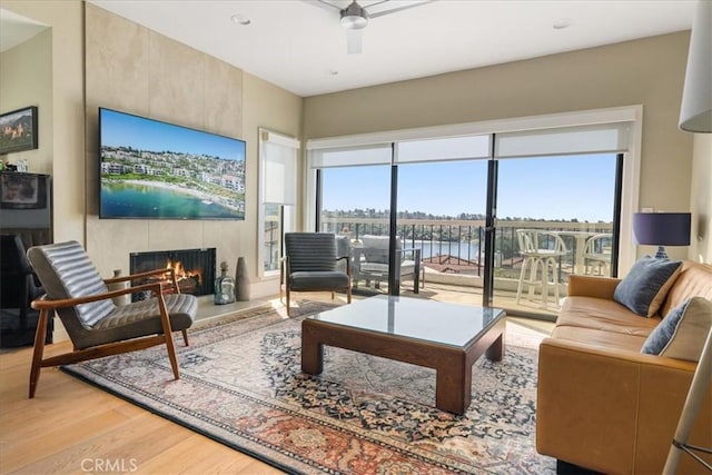 living room featuring a wealth of natural light, a ceiling fan, wood finished floors, and a tile fireplace