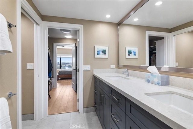 ensuite bathroom with tile patterned flooring, double vanity, connected bathroom, a sink, and baseboards