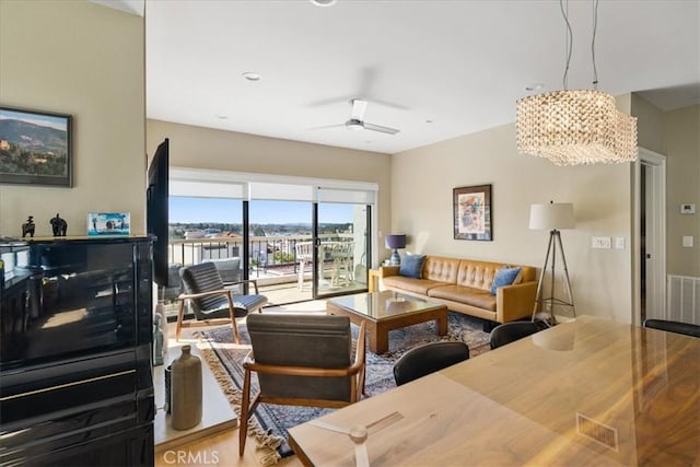 living area with ceiling fan with notable chandelier and visible vents