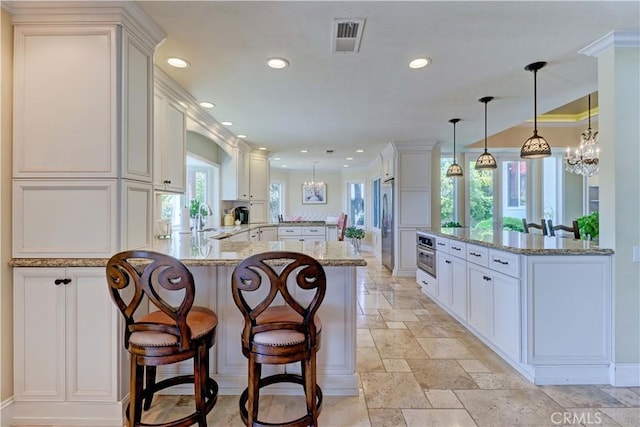kitchen with visible vents, a sink, baseboards, a peninsula, and recessed lighting