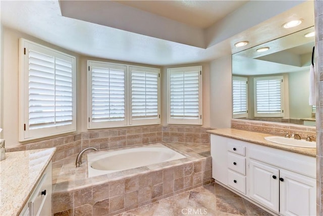 bathroom with vanity, a tray ceiling, and a bath