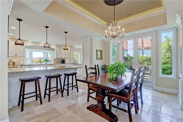 dining room featuring stone tile flooring, ornamental molding, recessed lighting, a tray ceiling, and a notable chandelier