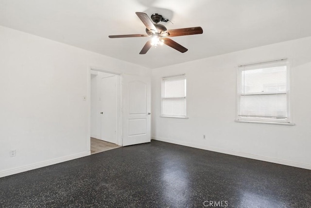 empty room featuring a ceiling fan and baseboards