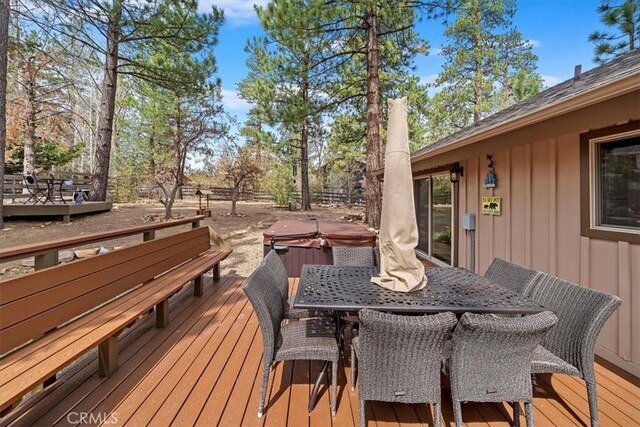 deck with a hot tub and outdoor dining space