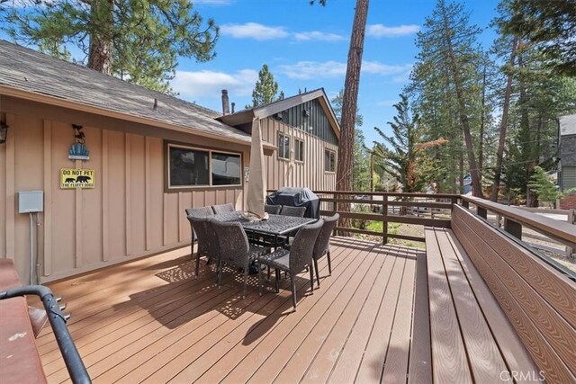 wooden deck featuring outdoor dining area and a grill