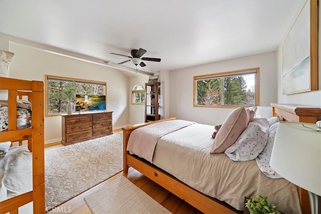 bedroom with ceiling fan, multiple windows, and wood finished floors