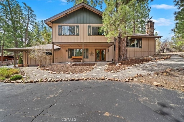 chalet / cabin featuring fence, covered porch, and a chimney