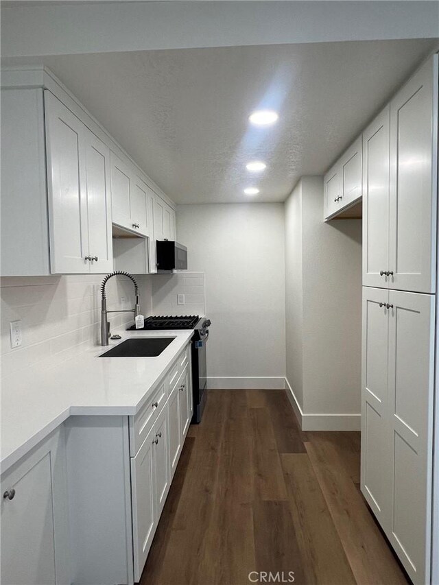 1400 W Warner Ave Unit 60, Santa Ana, CA 92704 - kitchen with white cabinetry, baseboards, range with gas stovetop, and a sink