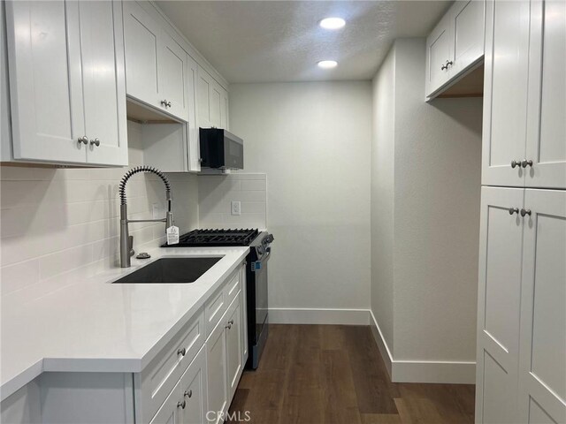 1400 W Warner Ave Unit 60, Santa Ana, CA 92704 - kitchen featuring dark wood finished floors, backsplash, light countertops, a sink, and baseboards