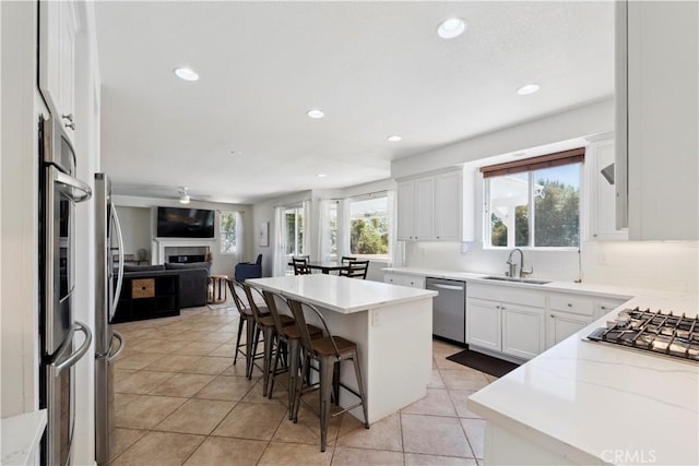 1732 Gamble Ln, Escondido, CA 92029 - kitchen with stainless steel appliances, open floor plan, a fireplace, a breakfast bar area, and ceiling fan