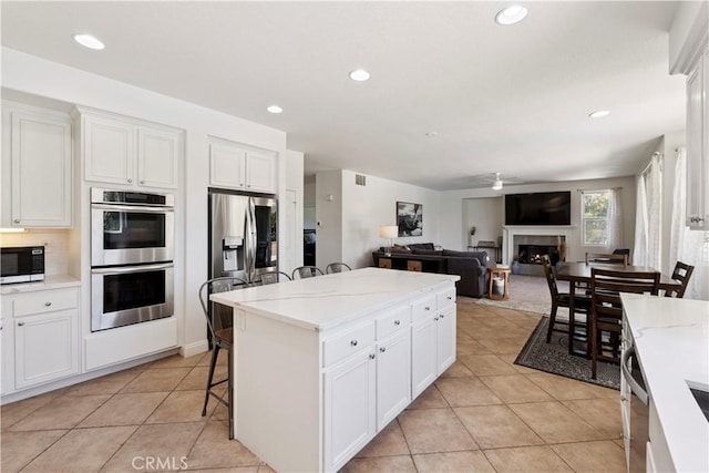 1732 Gamble Ln, Escondido, CA 92029 - kitchen featuring appliances with stainless steel finishes, a warm lit fireplace, light tile patterned floors, a kitchen island, and recessed lighting
