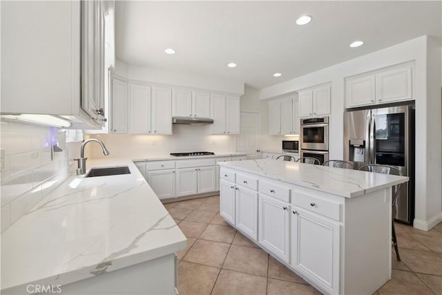 1732 Gamble Ln, Escondido, CA 92029 - kitchen featuring appliances with stainless steel finishes, under cabinet range hood, a kitchen island, light tile patterned floors, and white cabinetry