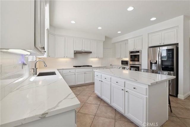 1732 Gamble Ln, Escondido, CA 92029 - kitchen with appliances with stainless steel finishes, under cabinet range hood, a center island, tasteful backsplash, and white cabinets